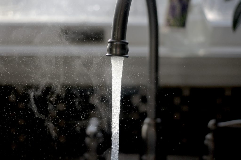 Un robinet où coule de l'eau chaude qui fait de la vapeur d'eau