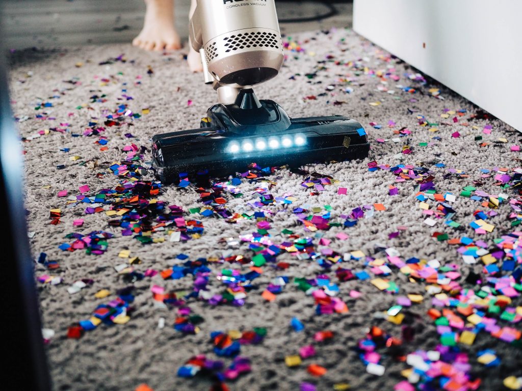 Un aspirateur qui nettoie un tapis recouvert de confettis